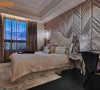 床头墙面以金色系为轴，宽窄不一的绷皮拼接编织感的皮革，V型图腾创造空间的动感与层次。