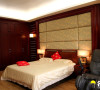 主卧的背景墙采用与窗帘一样的软包布，将浪漫氛围提升，黄花梨实木床与家私在整体的材质十分协调