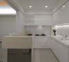 白色基底的厨房空间，半开放式的设计维持良好通风度，而吧台下方镜面贴覆有着反射、放大餐厅巧用。