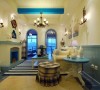 房间的整体色调就是蓝白亮色，如同希腊靠海的建筑一般，很清新的赶脚。壁炉的设计，还有船舵的小装饰，都比较能凸显欧式风格。地板铺的蓝色瓷砖和墙壁底部的木质设计，显得非常有层次。狭长的客厅空间也别有情趣吧！