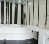 黑白间条的墙壁充满时尚感，与白色浴缸、黑色地板砖相得益彰。