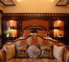 房间一角的休息区，沙发使用红黄相间的花纹作为主色，骑士花式的抱枕增加沙发的可读性，挑空的空间装饰以奢华水晶灯，四周的只见光不见灯的设计添加了房间的厚重与奢华。