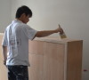木艺工人正细心为柜体刷灰、打磨，为它的“艺术人生”，添姿加彩