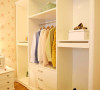 靠墙放置的简约白色衣柜，既可以收纳衣物，又能展示装饰品。