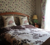 对于卧室床品的选择，设计师选择了素雅的白、紫相间的棉麻制品，大朵牡丹的窗帘和小碎花的壁纸也是为了映照卧室的闲适。在经过适当的搭配之后，简单的饰品共同构成了乡村气息浓厚的别墅空间。