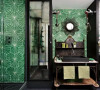 绿色卫生间的台盆安在一个老的金属架子上。黑色台盆与绿色墙砖相映成趣。吊灯以及掩藏在老式镜子后面的壁橱。