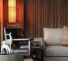 在带有浓郁木质纹理的沙发背墙前，一盏仿旧的设计款吊灯晕染了空间的禅意宁静。