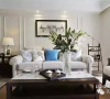 明净透亮的客厅，暖白沙发显得格外清爽，脚凳与靠垫的中式花鸟元素使本就明 媚的空间，多了灵动与生气。