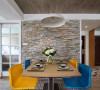 餐厅背景是一面墙的文化砖，蓝色和黄色的现代感餐椅。
