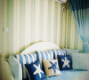 沙发床上的布艺通过一些彩色海星，贝壳，栅栏，蓝色的布艺窗帘来达到地中海的感觉。