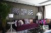 客厅紫色的沙发、白色边几、不锈钢黑色玻璃的茶几这都是轻古典港式的代表，为了使空间不呆板，这里添加了高级灰暗花壁纸的主体墙，以及有皮草风格的无框装饰画，从此让整个客厅有了时尚轻古典港式的时代感。