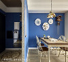 为避免一进门便面对客厅，玄关增设的墙面顺势成了餐厅装饰的一环，纯蓝墙面搭配圆形吊饰以及彩绘吊灯，让用餐氛围更加惬意。