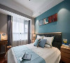 主卧地面通铺木地板，一面蓝色床背景点缀长条装饰画，辅以灯光制造层次，整体空间休闲舒适