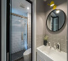卫生间做了干湿分离，地面和墙面还是主色调低调的浅灰色，圆形镜子上有一个黄色的小臂灯，用来补充照明。