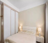 一张舒适整洁的大床，木色配以白色的移门大衣柜，满足卧室的基本功能
