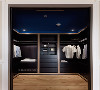 男主卧更衣室，以双色木皮搭配呈现绅仕质感，沿用起居室的深蓝色作为顶盖色彩，沉稳而独特。